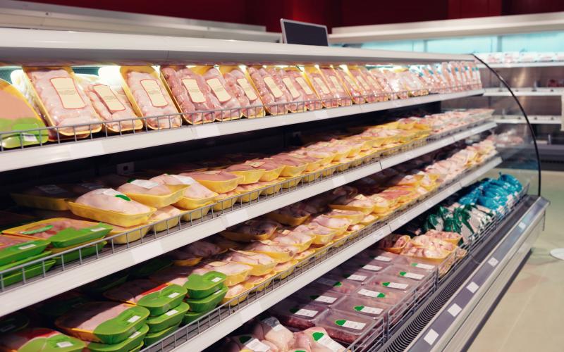Various packaged poultry products on display in a cooler at a grocery store.