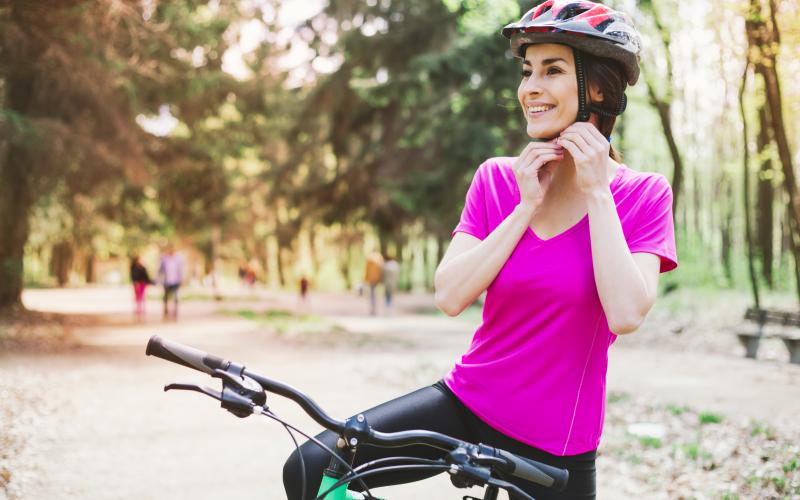 Bike safety Woman in pink shirt buckling helmet under her chin