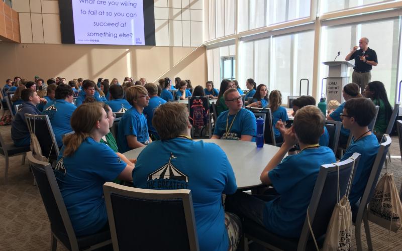 a man presenting in front of a group of young people.