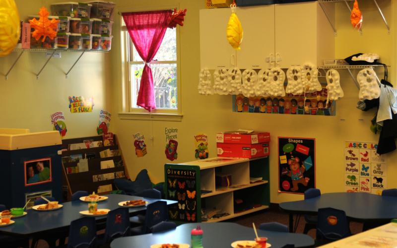 Lunch room in a daycare facility with plates set on the tables and fall decorations in the background.
