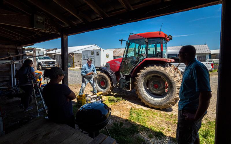 A group of dairy employees having a discussion around a barbecue grill.