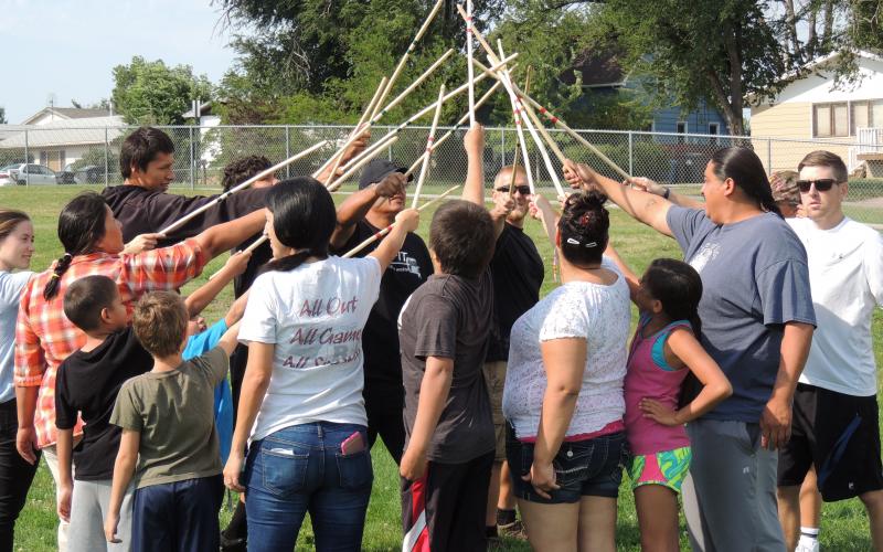 Group of adults and children playing doubleball game in a field