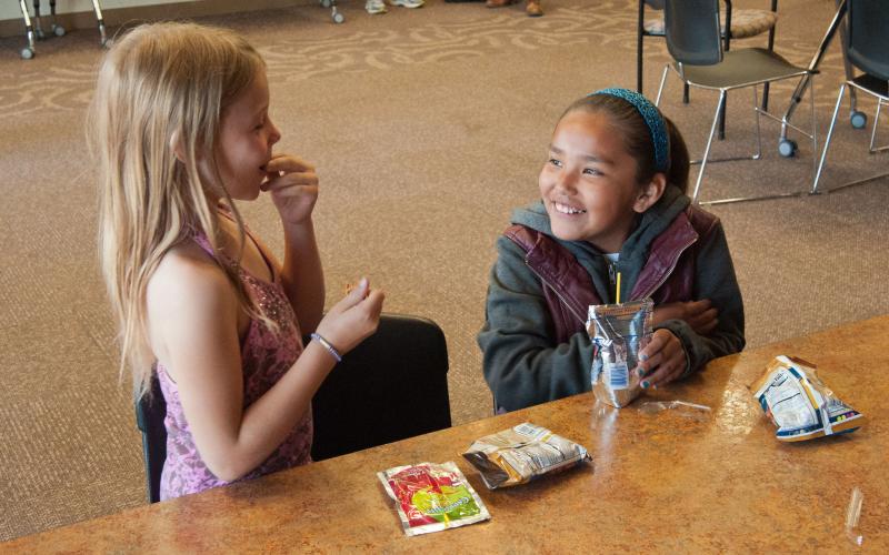 Two young girls enjoying healthy snacks after school. Courtesy: Bob Nichols, USDA [CC BY 2.0].