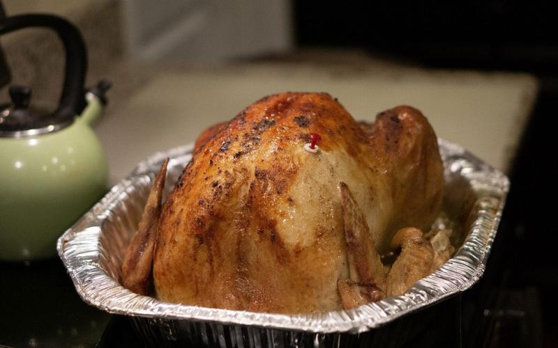 A roasted turkey in a tinfoil roasting pan.