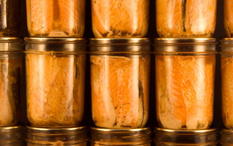Several jars of canned salmon filets stacked neatly on top of each other.