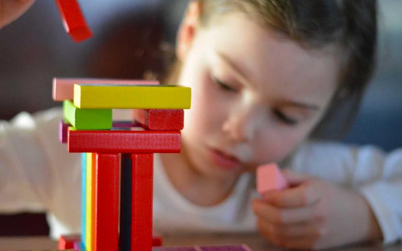 A young girl playing with colored wooden blocks.