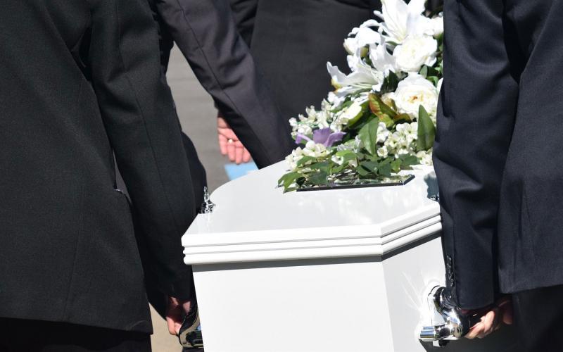 A group of men carrying a white coffin.