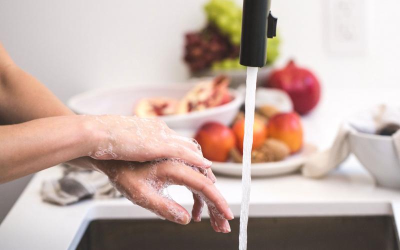 A woman washing her hands in the kitchen sink.