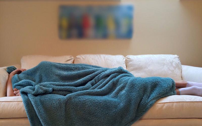 A person sleeping under a blue blanket on a white.