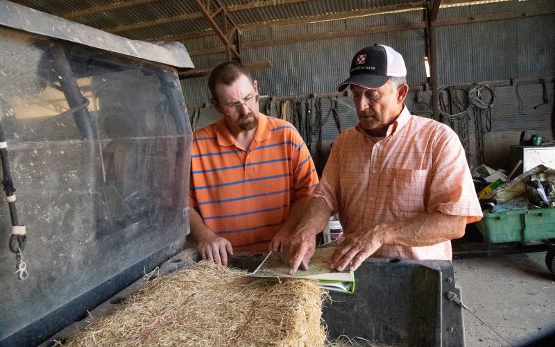 A rancher and RMA agent reviewing insurance paperwork beside a off-road vehicle.