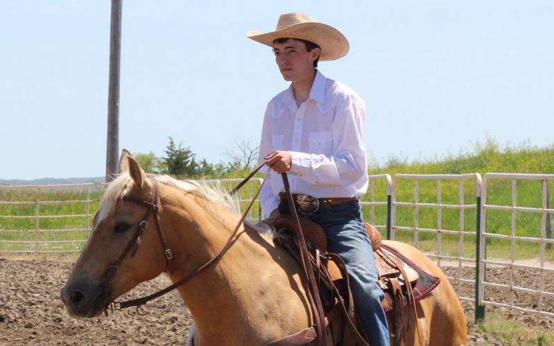 Frank Huber riding a tan horse in a corral.