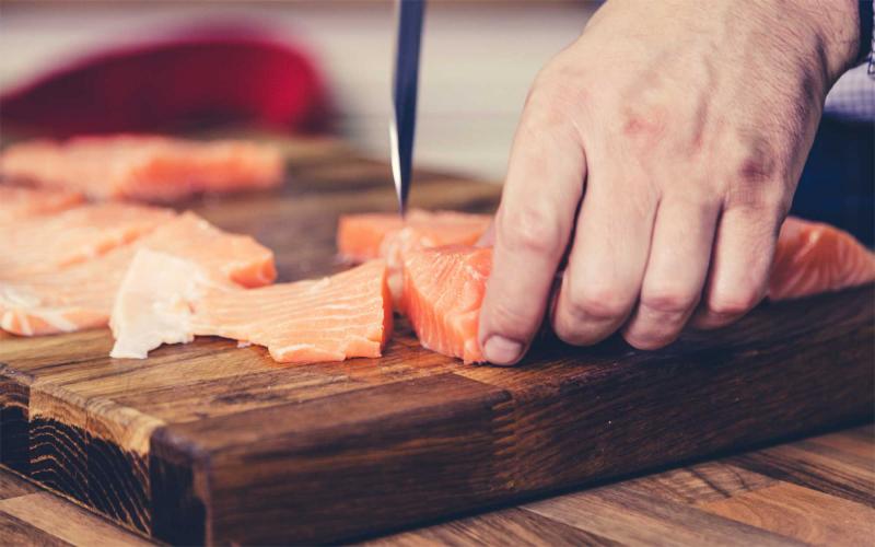 Man cutting salmon into pieces for home canning.