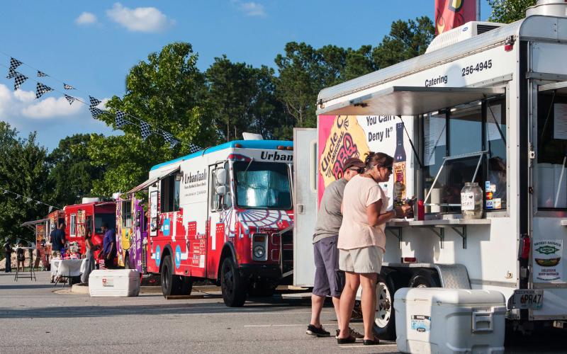 A series of food trucks lined up at a community event.
