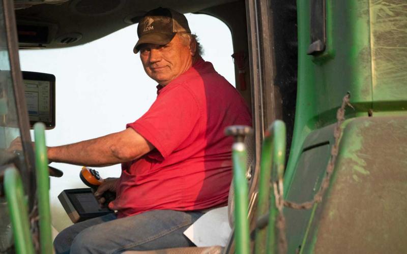 Farmer calibrating a yield monitor insde a combine cab.