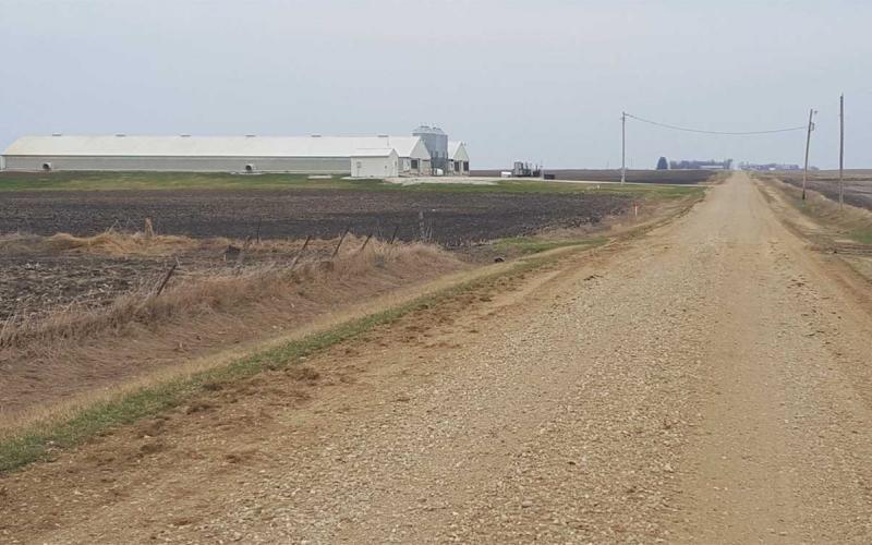 Gravel road with swine barn in the distance.
