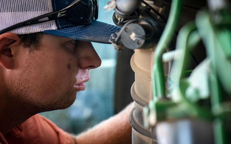 Farm employee inspecting a piece of heavy machinery.