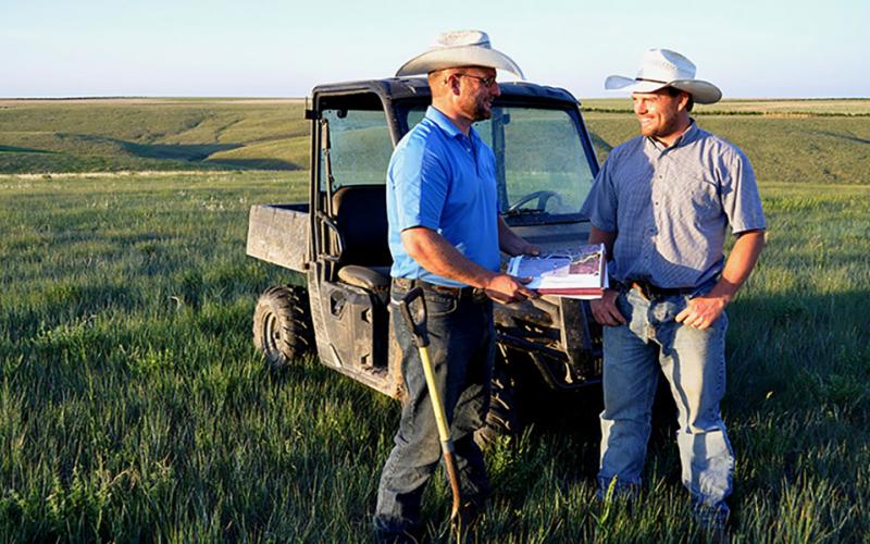 Two ranchers in a pasture reviewing a mangement plan.