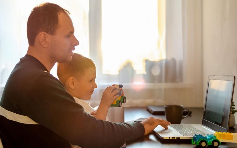 Father and son participating in a remote meeting at home.