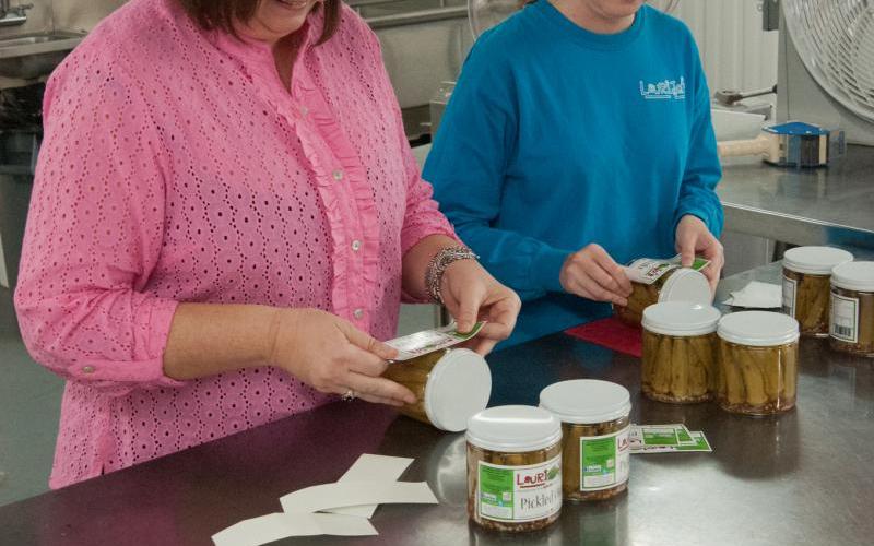 a mother and daughter putting labels on home-canned food products. Photo by Stephen Ausmus, USDA