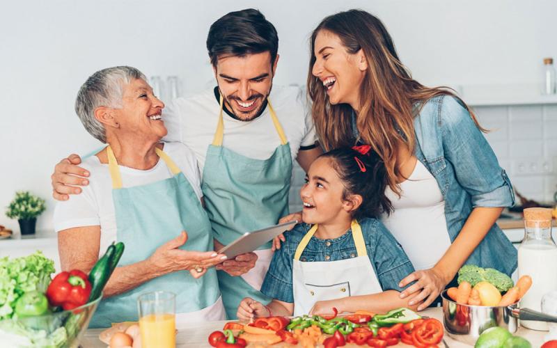 Grandmother, parents, and daughter preparing vegetables in a kitchen.