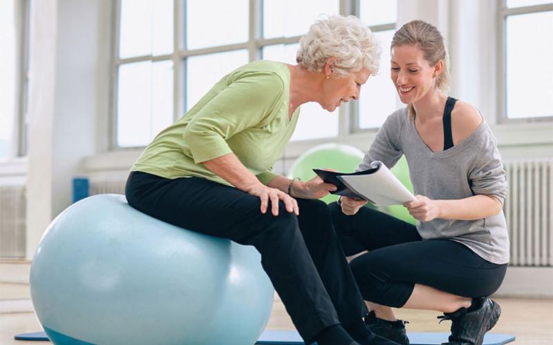Senior woman and health coach looking at a health report in a gym.
