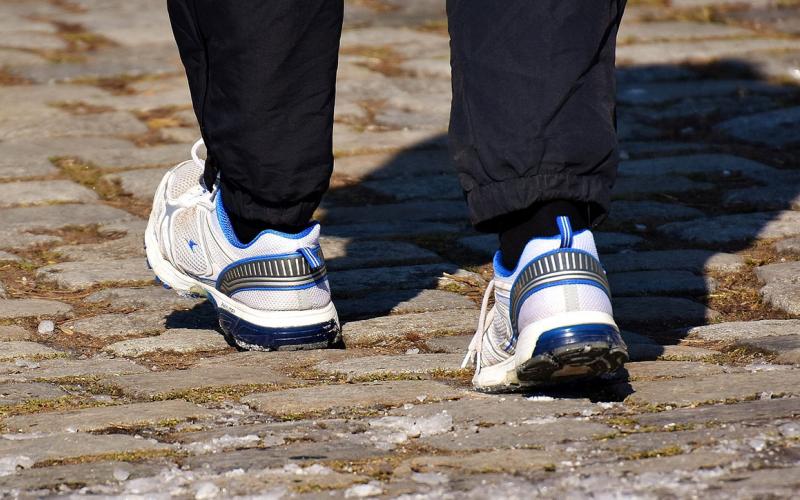 Person walking outdoors wearing a pair of comfortable walking shoes.