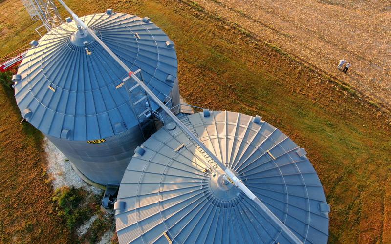 Two large grain bins next to a recently harvested field of soybeans.