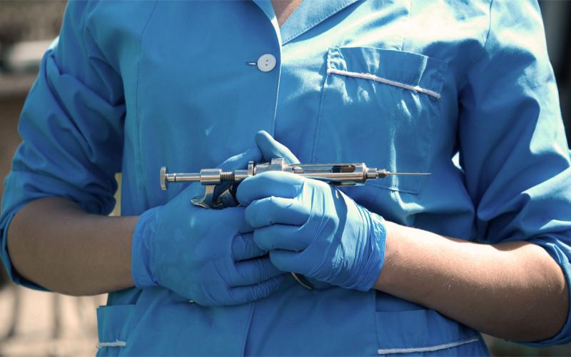 Veterinarian holding a syringe gun for animal vaccinations.