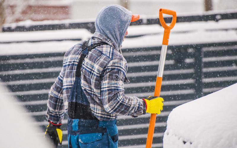Dairy employee in winter clothing holding a shovel.