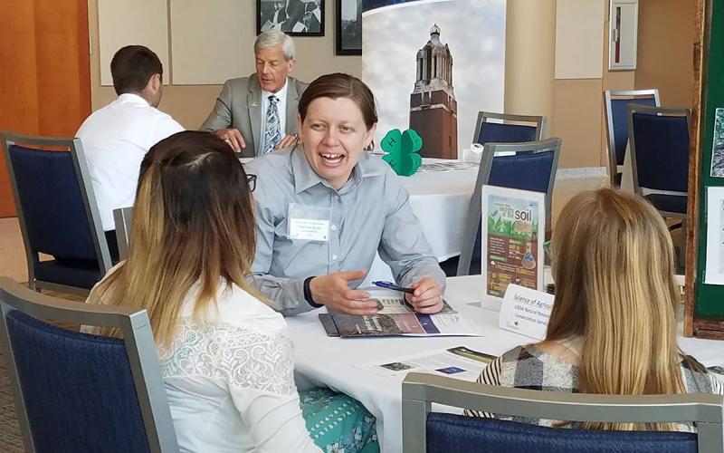4-H volunteer discussing an exhibit with two 4-H youth.