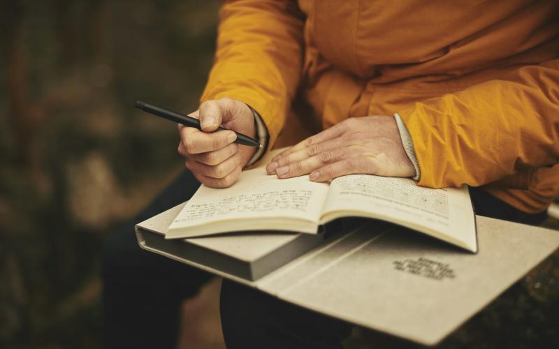 a person in an orange outfit writing with a pen in a book