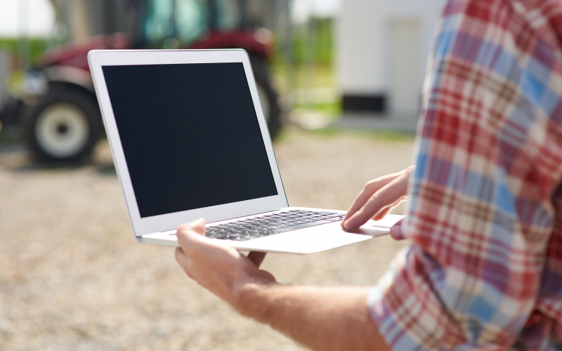 a person in a red and blue plaid shirt holding a laptop outdoors
