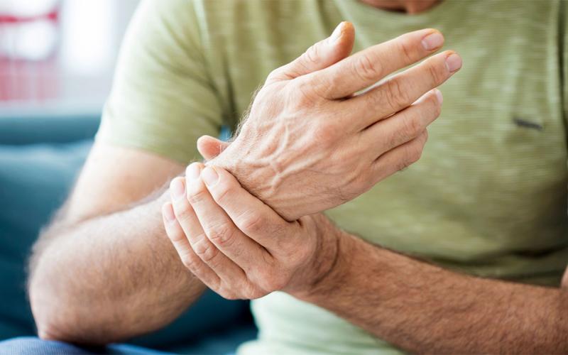 Man holding his wrist, which is afflicted with arthritis.