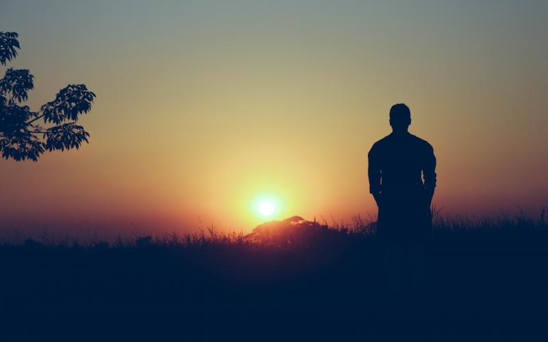 a person standing outside watching the sunset