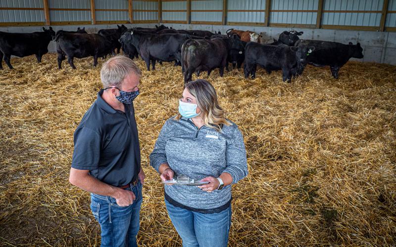 Producer and ag agent reviewing paperwork in a cattle shed.