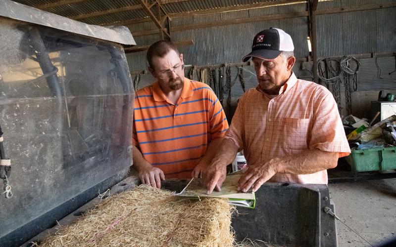 Landowner and producer in a machine shed reviewing a contract.