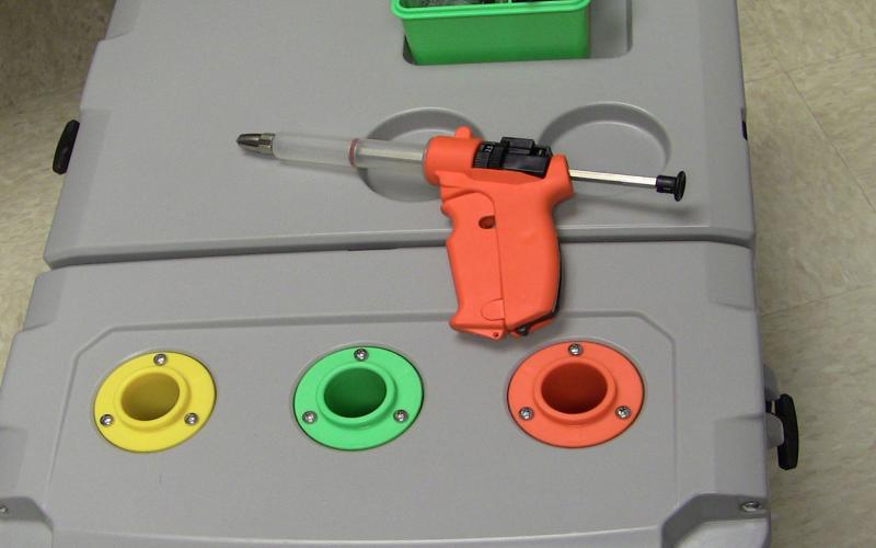 Heavy-duty cooler with color-coded slots for vaccines and a compartment for syringe and supplies.