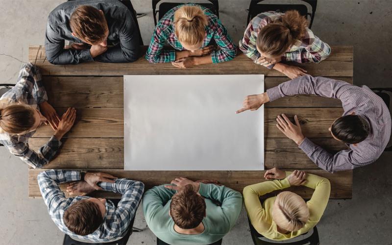 Small group of young professionals gathered around a meeting table.