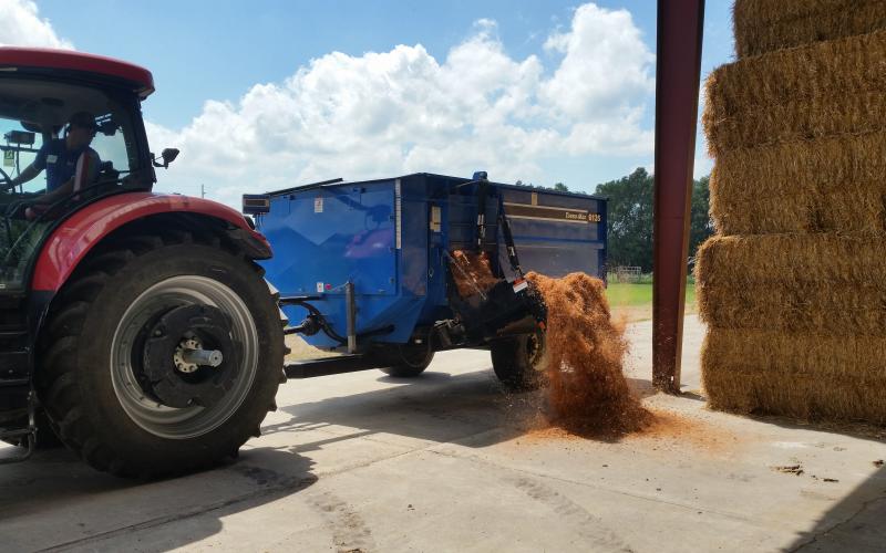 a tractor pulling a blue feed wagon
