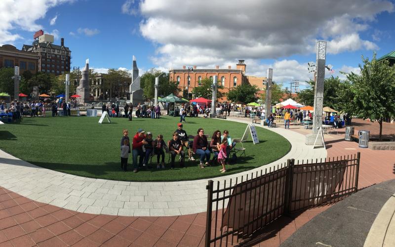 a bigger group of people in a town square doing various things