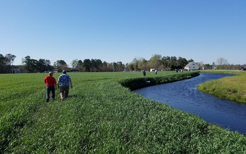 Two men walking near a drainage water recycling pond