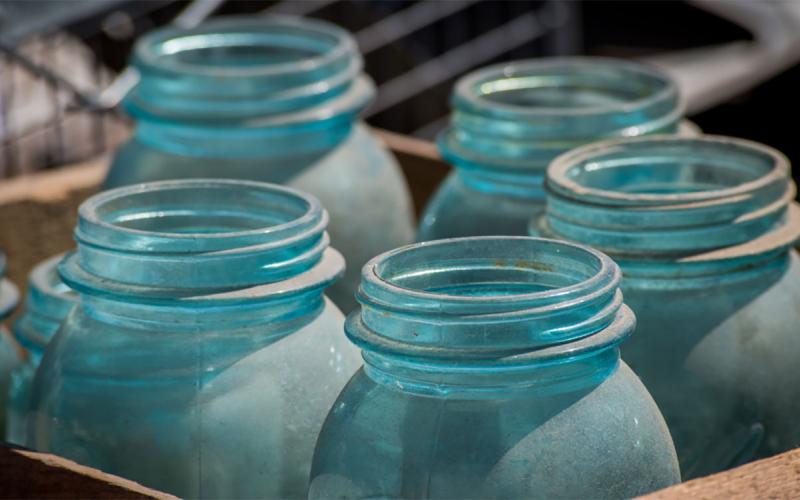 Blue-tinted antique canning jars in a brown box.