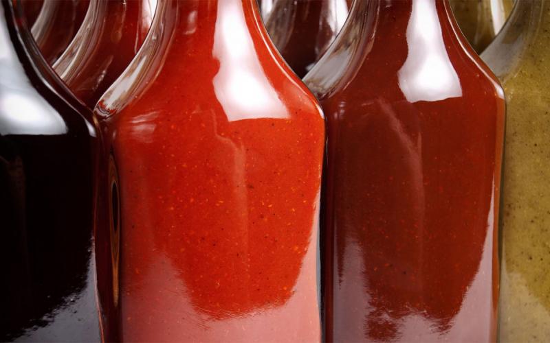 Several bottles of different hot sauces arranged on a counter.