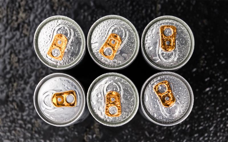 Six canned energy drinks on a dark slate.