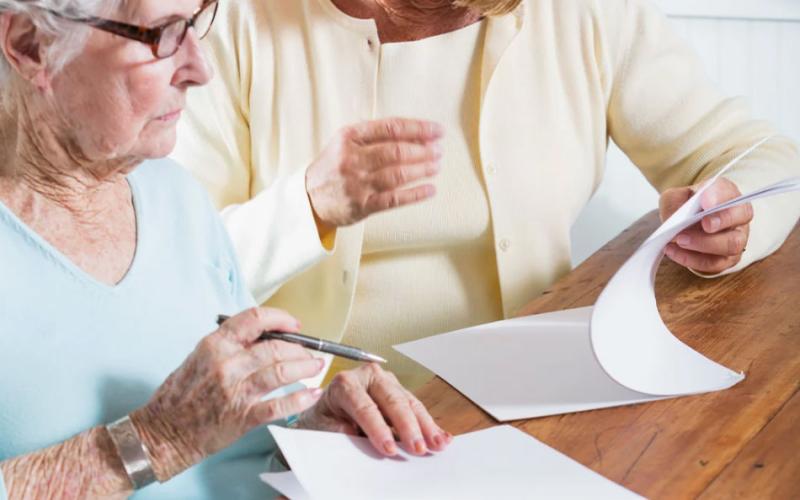 Mother and daughter reviewing paperwork at kitchen table.