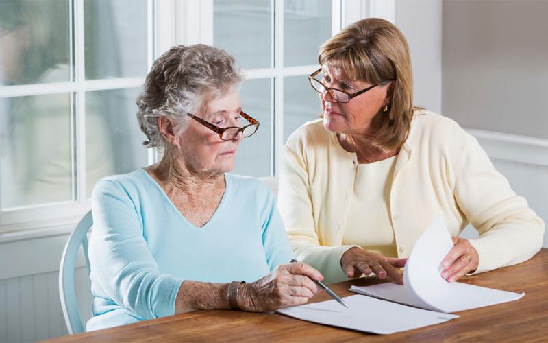 Mother and daughter reviewing paperwork at kitchen table.