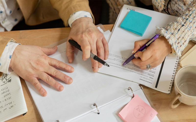 An older female adult reviewing written documents with her daughter.