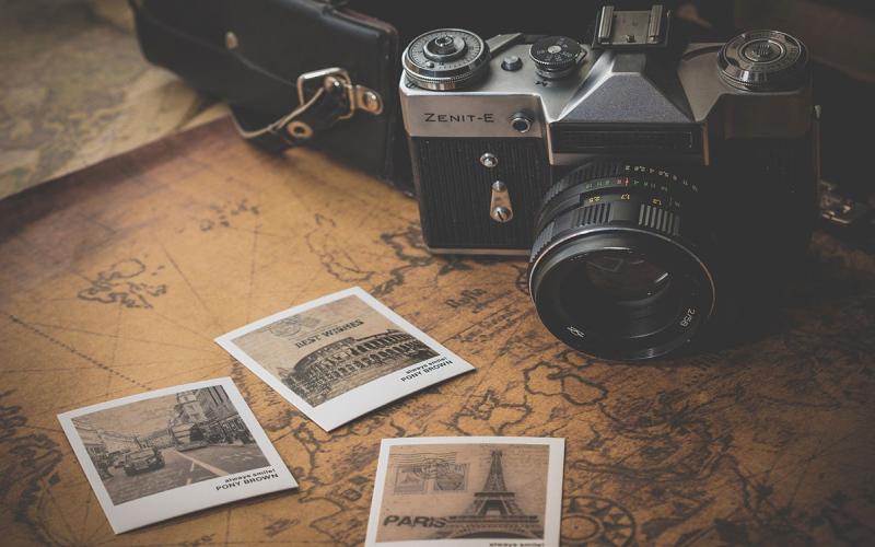 A camera and black and white photos sitting on top of a map.