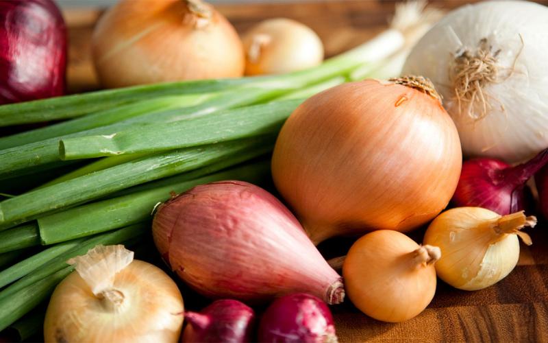 Variety of freshly harvested onions on a cutting board.