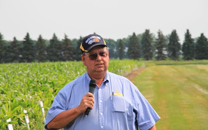 Paul O. Johnson giving a presentation near a research plot.